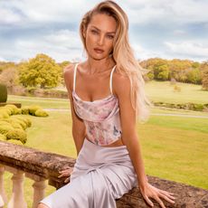 Candice Swanepoel wears a floral corset in front of a garden backdrop