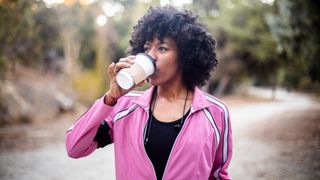 Young woman drinking coffee while out walking