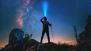 A hiker with headlamp stargazes