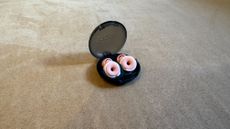 Loop Switch earbuds on a pink surface in the case with the lid open