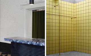 Left, a square patterned reception counter with a white and blue marble top in front of a green accordion door. Right, a wall with square yellow tiles and bronze pipes on it.