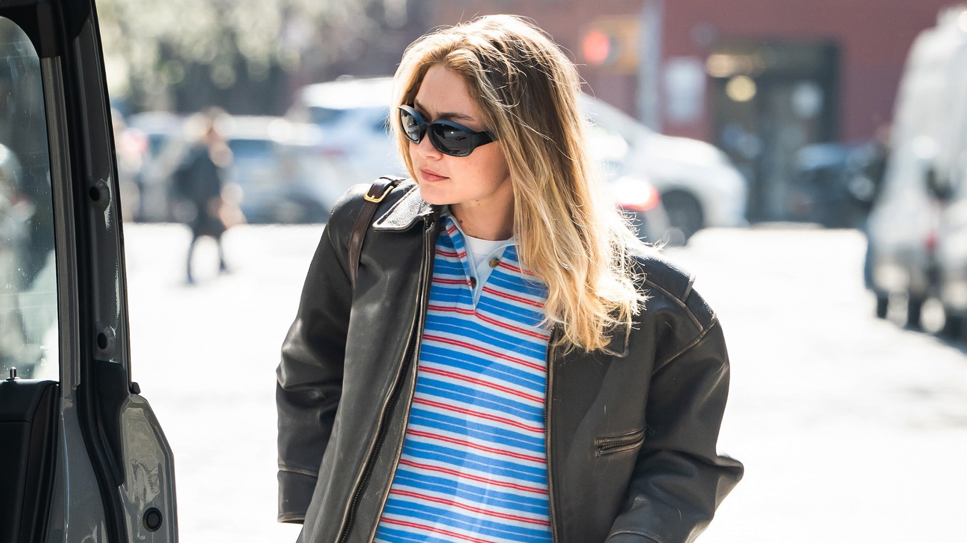 Gigi Hadid wearing a leather jacket, polo shirt, low-rise jeans, and ruched loafers in NYC
