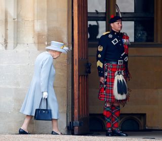 Queen Elizabeth II walks past The Queen's Piper, Pipe Major Richard Grisdale of The Royal Regiment of Scotland as she returns to Windsor Castle