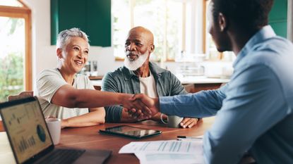 Cheerful older couple meeting a financial adviser in their home