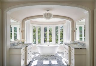 bathroom with freestanding bath centred in huge bay window with arched ceiling and vanity units either side of archway