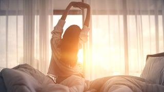 Woman waking up to the sunrise