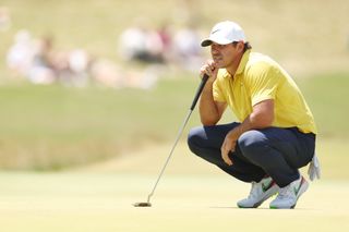 Koepka lines up his putt in a yellow shirt