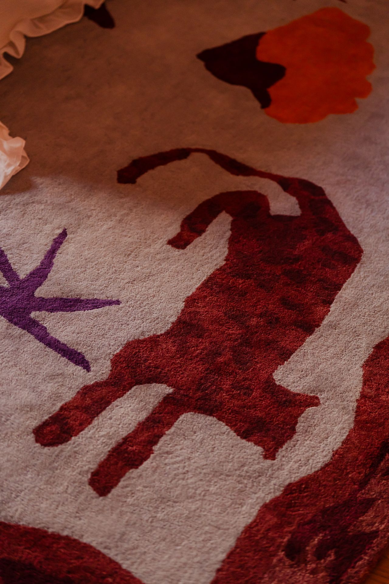 A closeup of a rug showing a cat-like motif rendered in red. 
