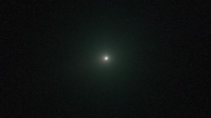 An image of comet 3I/ATLAS appearing as a white dot with a green hue.