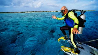 A scuba diver jumps into the water in Bonaire
