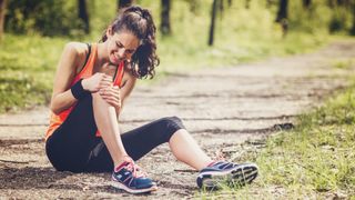 A woman sits on the trail after hurting her knee