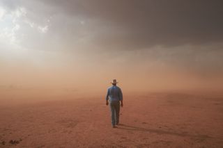 Un granjero caminando por un campo en medio de la sequía