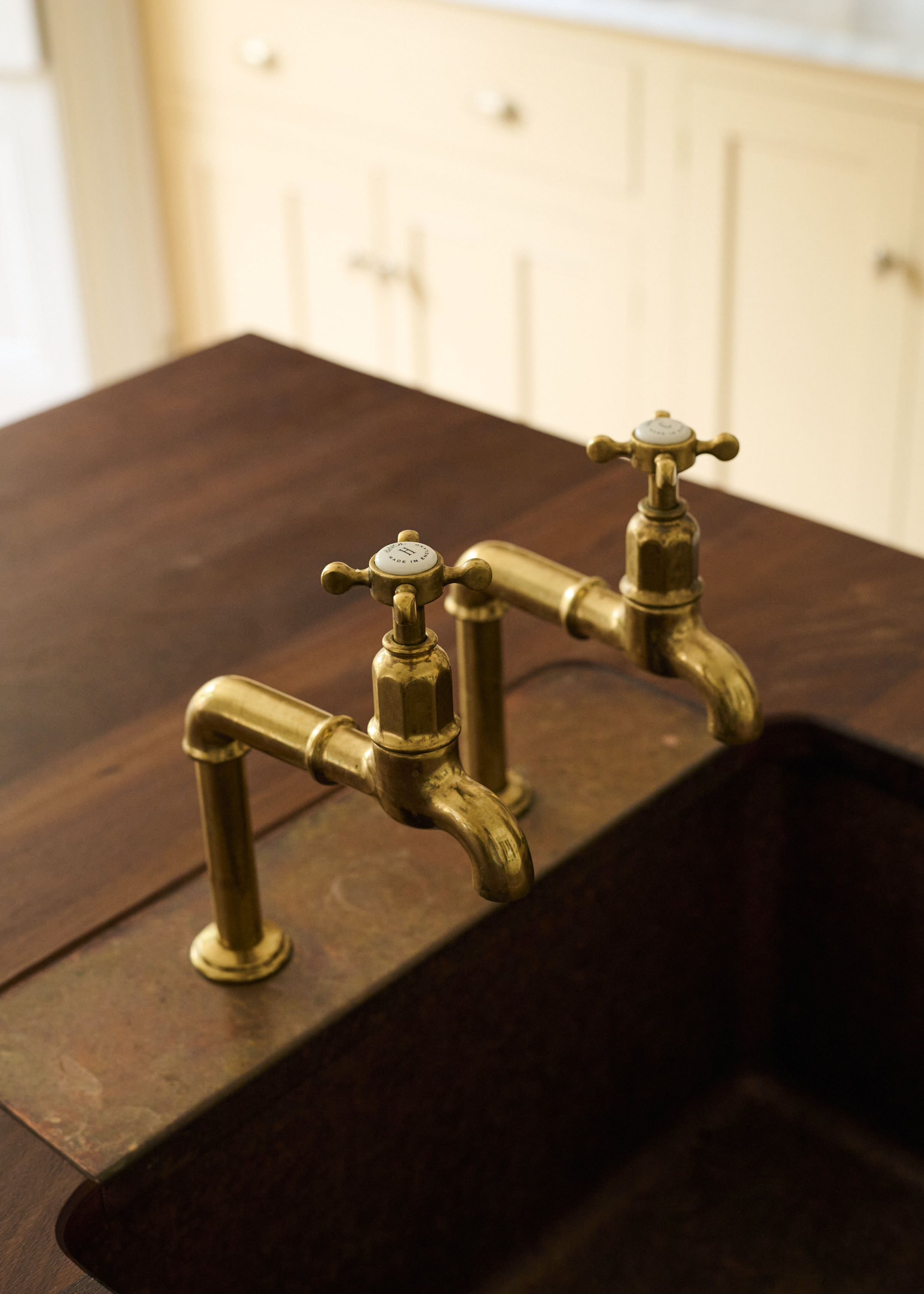 a close up of gold tap with a brown marble insert behind, within a wooden counter