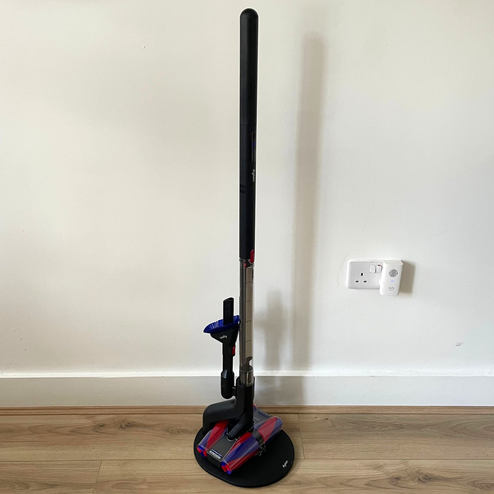 Dyson PencilVac standing on wood-effect flooring in front of a white wall