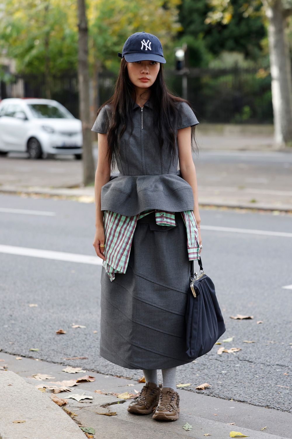 street style shot of woman in grey peplum top and skirt with brown trainers