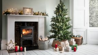 fireplace with stove in living room with white floorboards and Christmas tree
