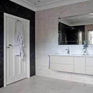 white tiled bathroom with washbasin and mirror