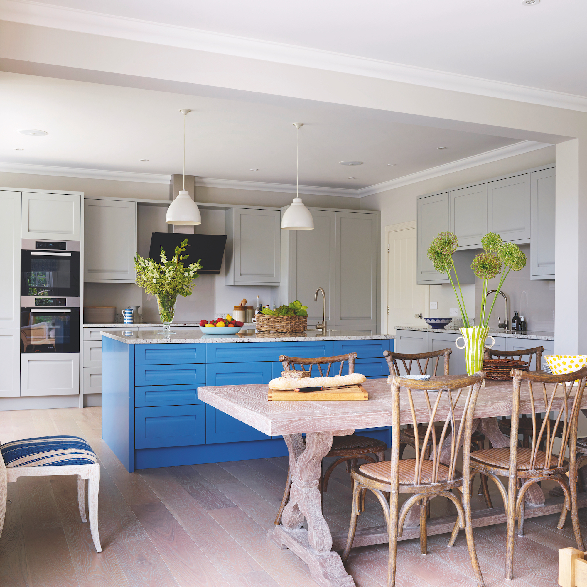 open plan kitchen and dining room with large blue kitchen island with pendant lights above