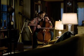 a man plays a cello in an apartment in a still from grimm