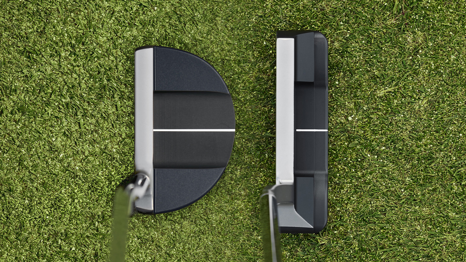 Looking down at two Bettinardi putters at address on a green