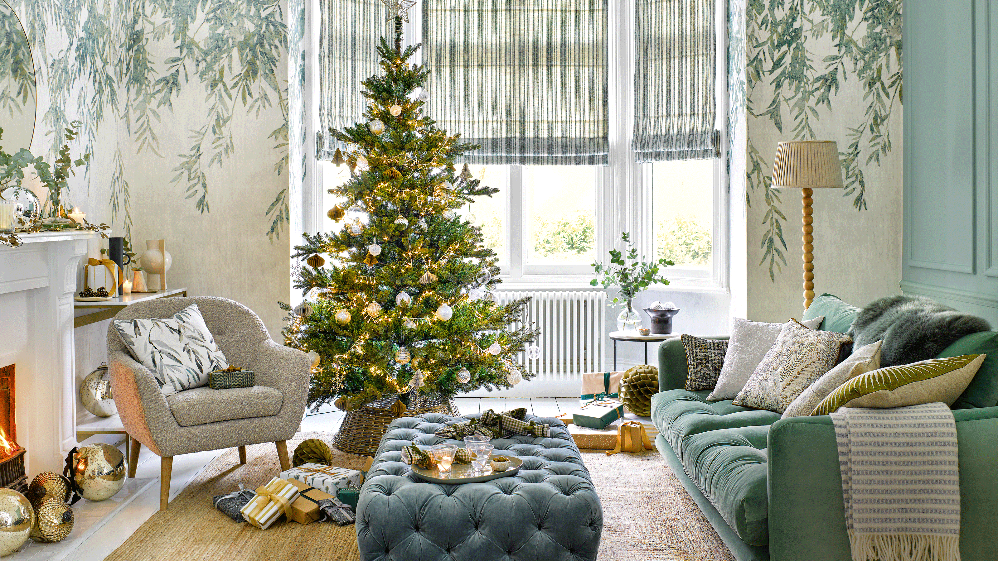 a pale green living room with a Christmas tree and a sofa, armchair and footstool