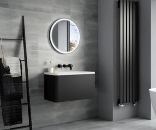 round mirror with LED light in grey tiled bathroom with black vertical radiator, vanity unit and towel rack