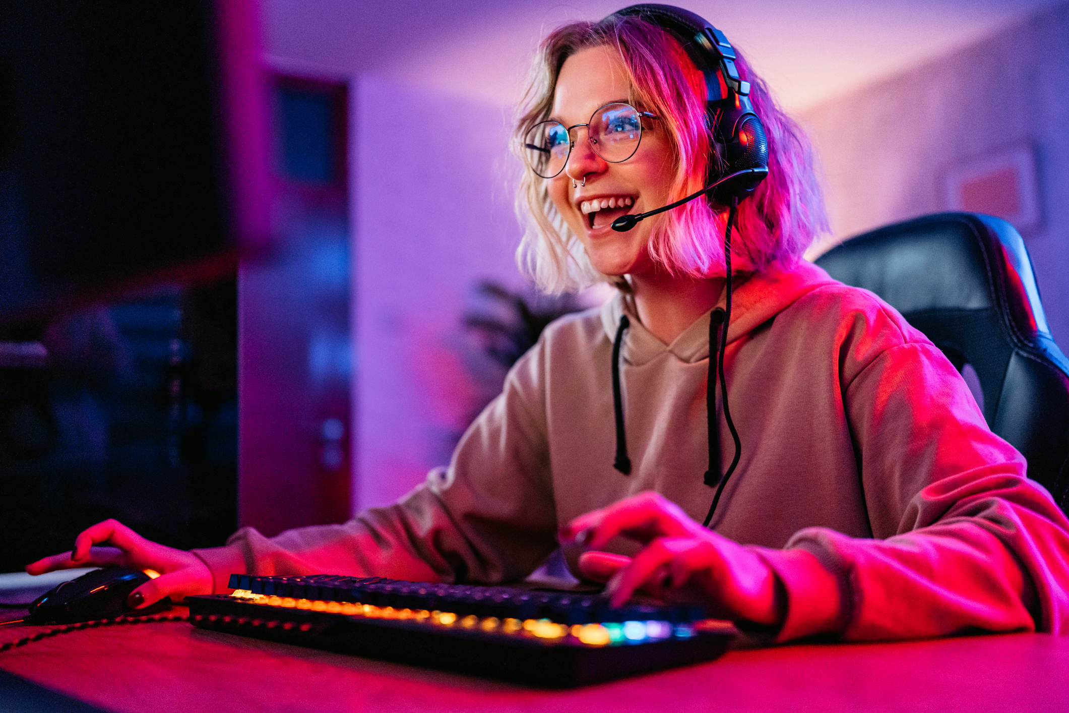 A woman gaming at her gaming desk in a pink glow.