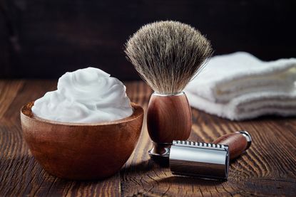Image showing face cream, a razor, a brush and wash cloth on a table