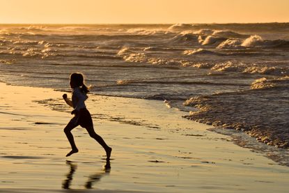 A young girl runs on the beach.