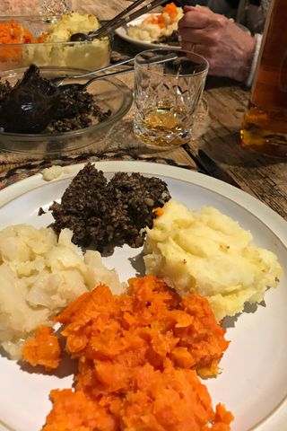 A plate of traditional Scottish neeps and tatties, haggis and a glass of whisky