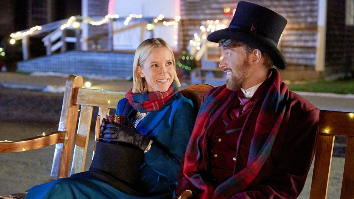 Jessy Schram ad Chandler Massey sit on a bench in Mystic Christmas