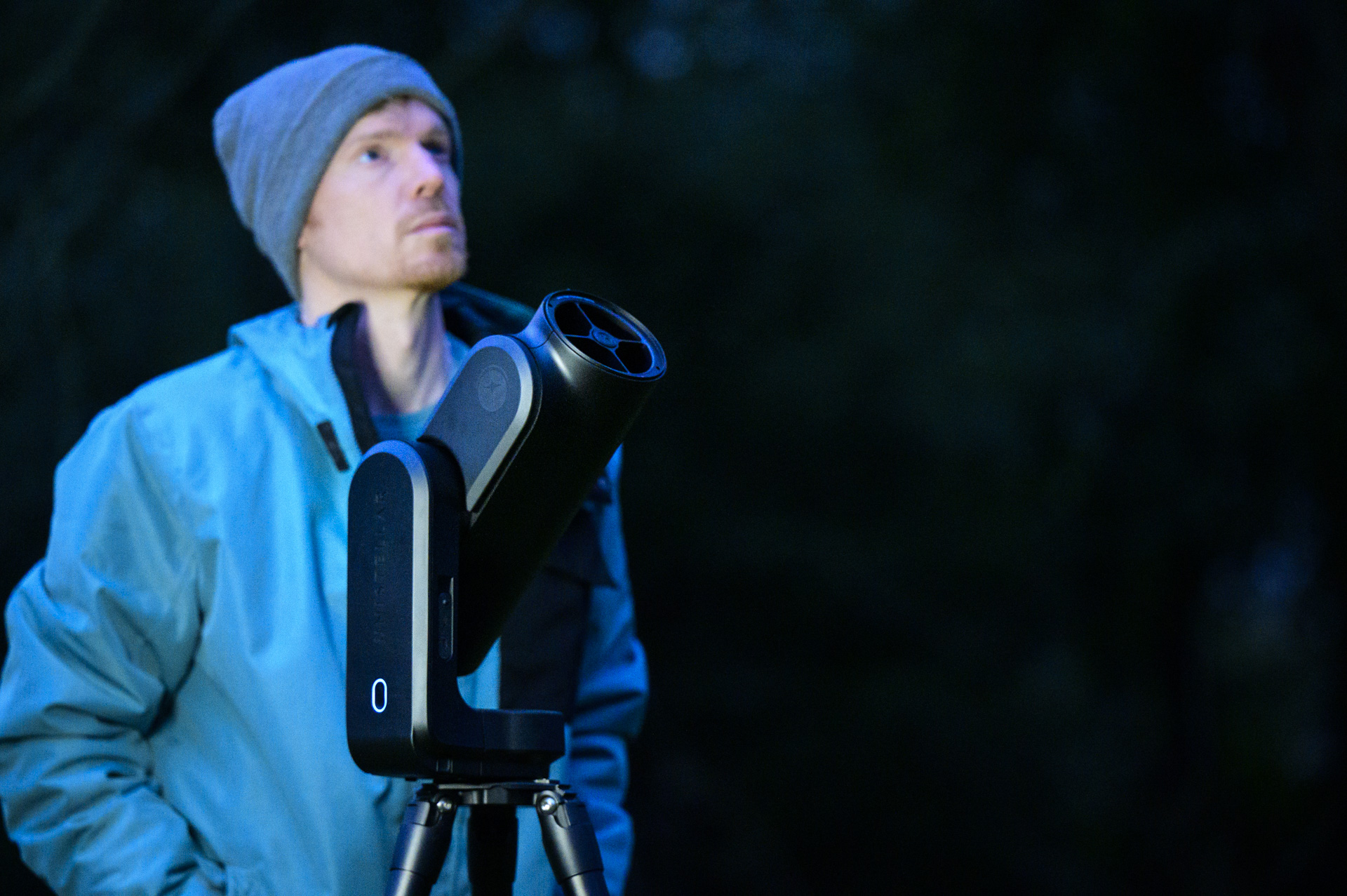 Person looking up and standing beside the Unistellar Odyssey Pro at dusk