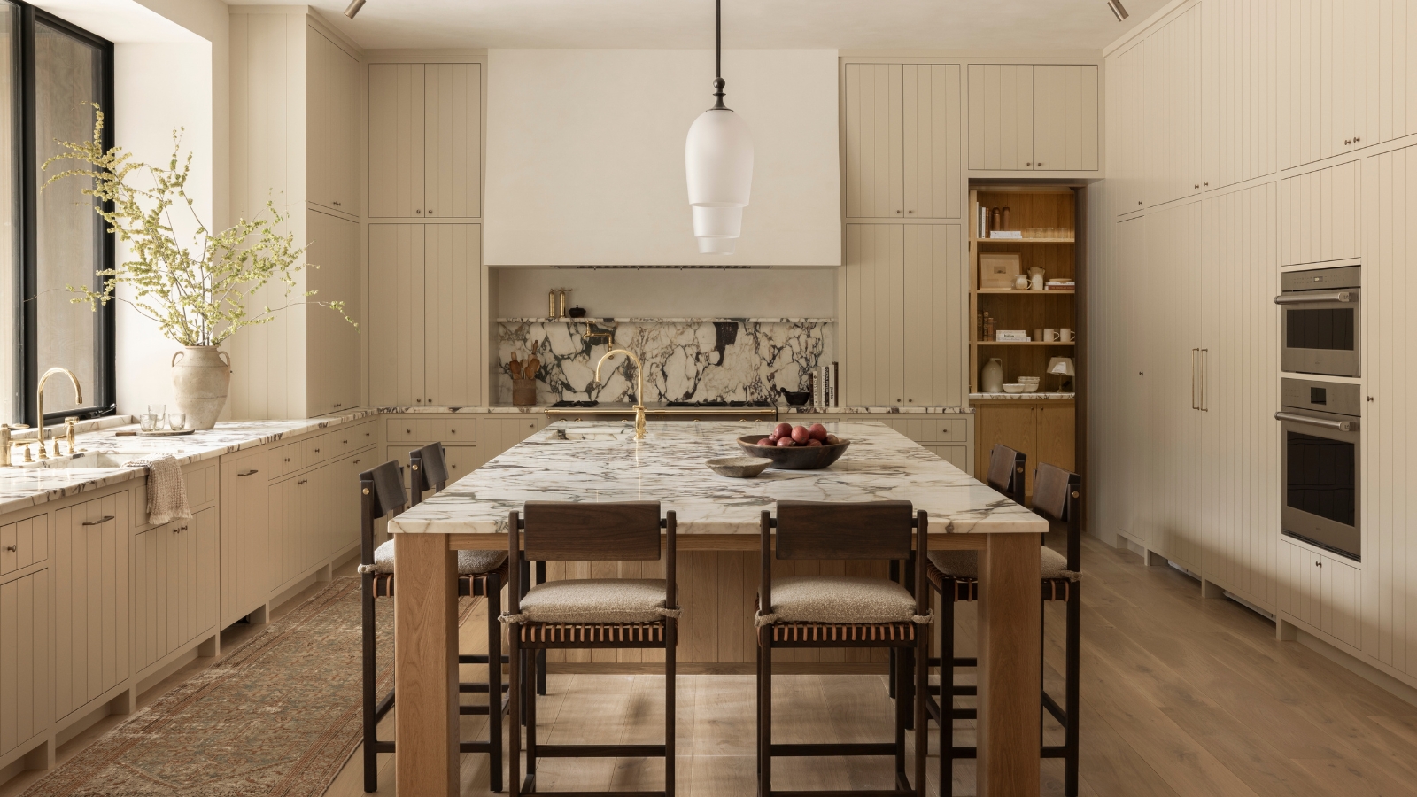 A warm cream kitchen with marble countertops and a wooden island
