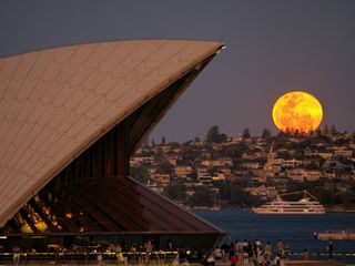 full moon shining bright with the sydney opera house on the left.