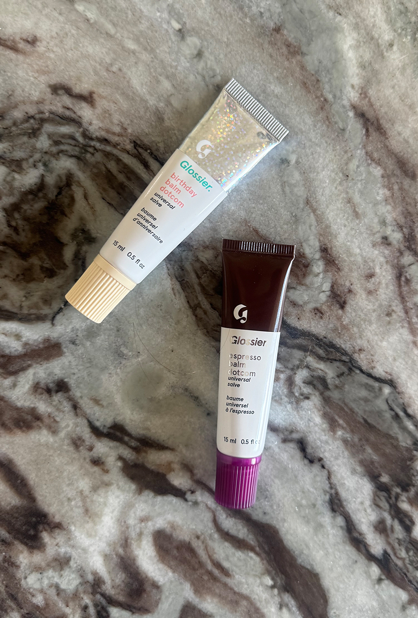 Glossier Balm Dot Com lip balms on marble table