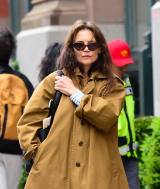 Katie Holmes in New York City April 2024 wearing a khaki coat and carrying a black bag