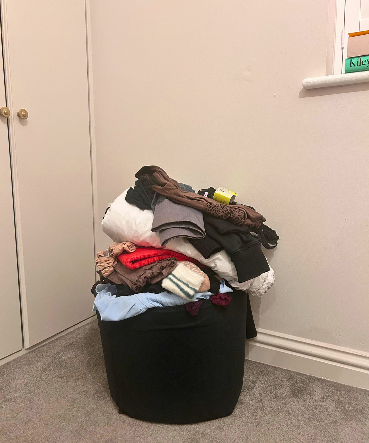 A pile of clothing sat in a box in a beige room