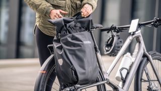 a pannier being placed on the rear rack of the Orbea Diem e-bike