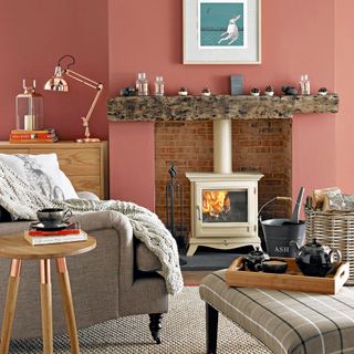 Terracotta living room with fireplace with wooden mantel and cream wood burner