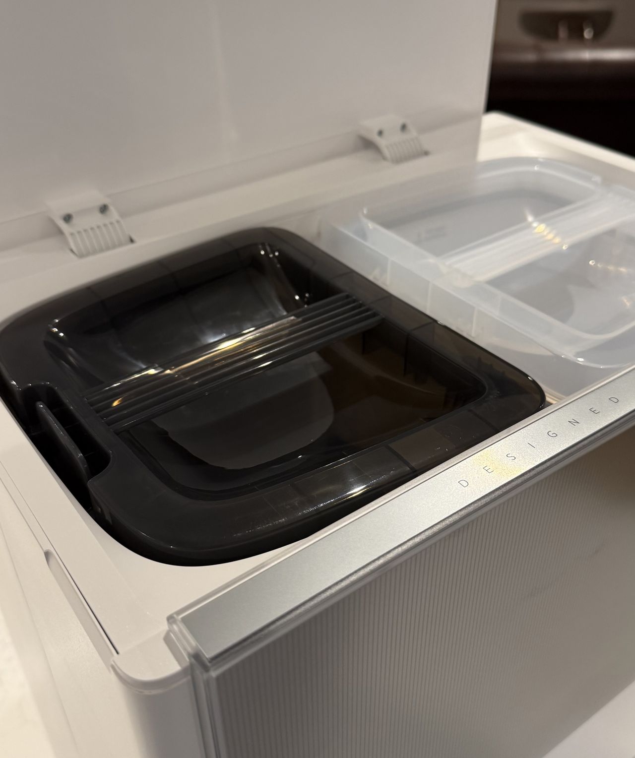 Close-up of the Dreame Aqua10 Ultra Roller dock showing the clean water tank and dirty water tank compartments under the open lid.