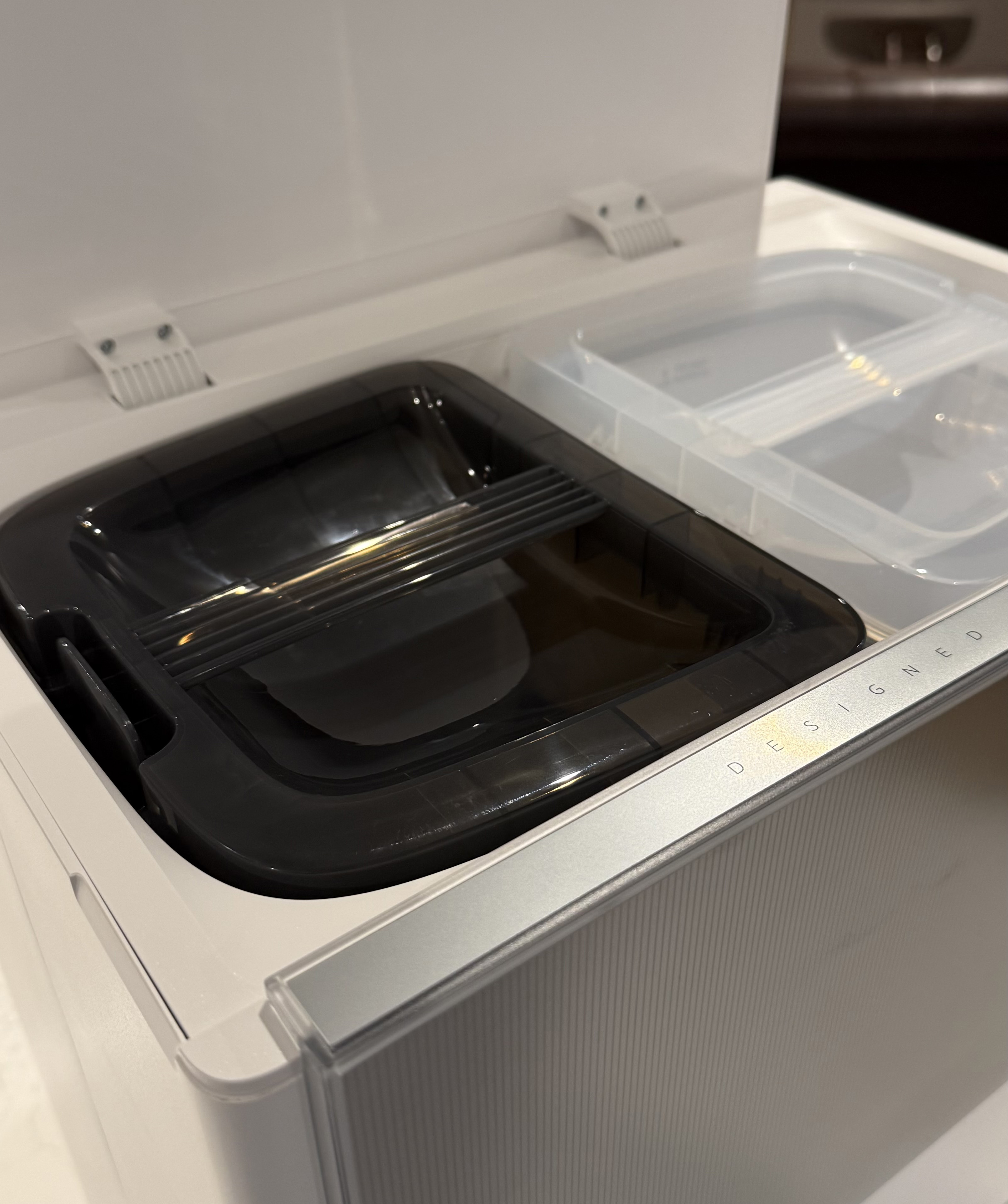 Close-up of the Dreame Aqua10 Ultra Roller dock showing the clean water tank and dirty water tank compartments under the open lid