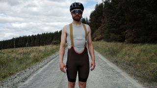 A man standing on a gravel track wearing the MAAP Alt-Road bib shorts
