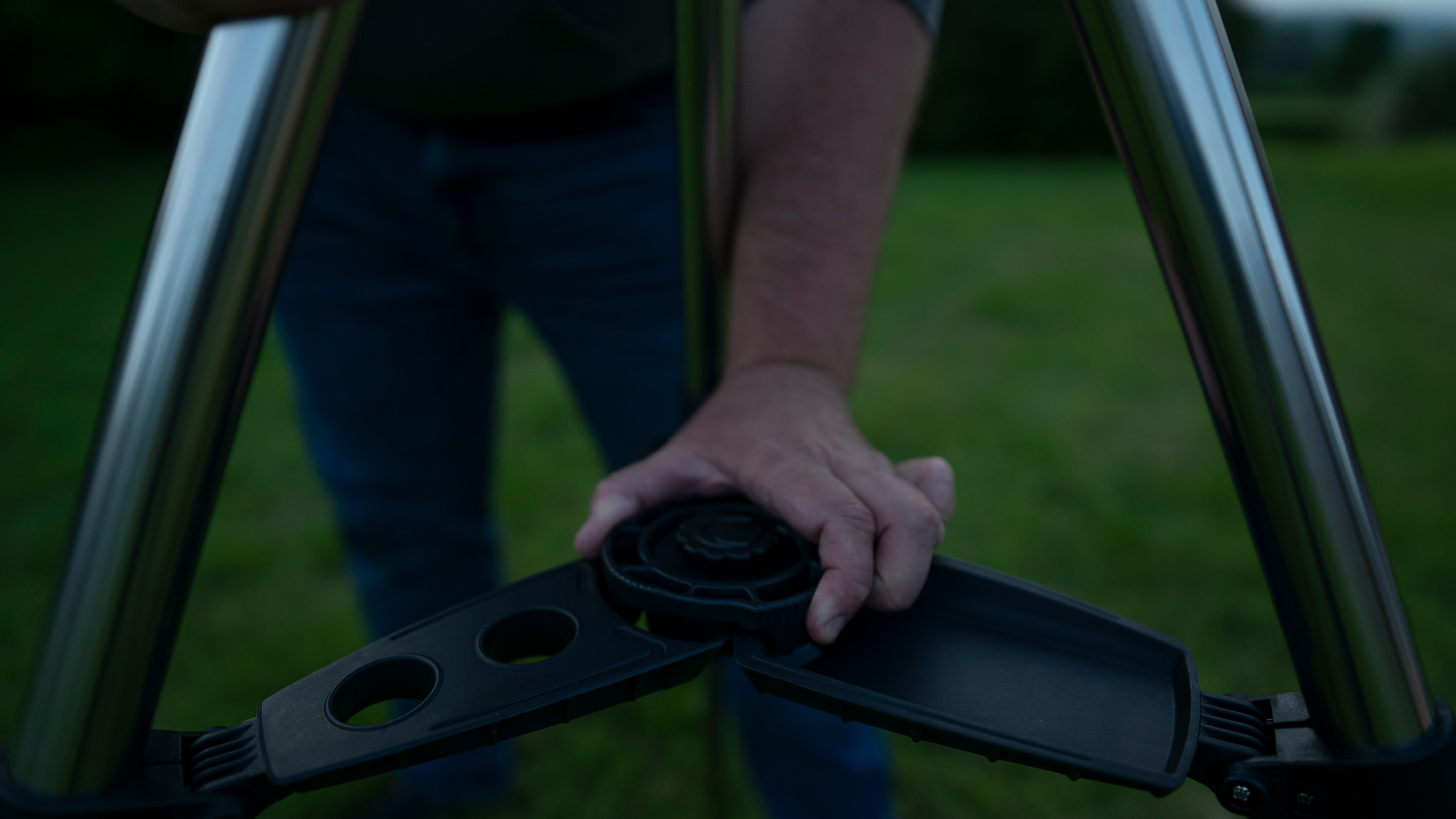 Man setting up a telescope tripod in a field