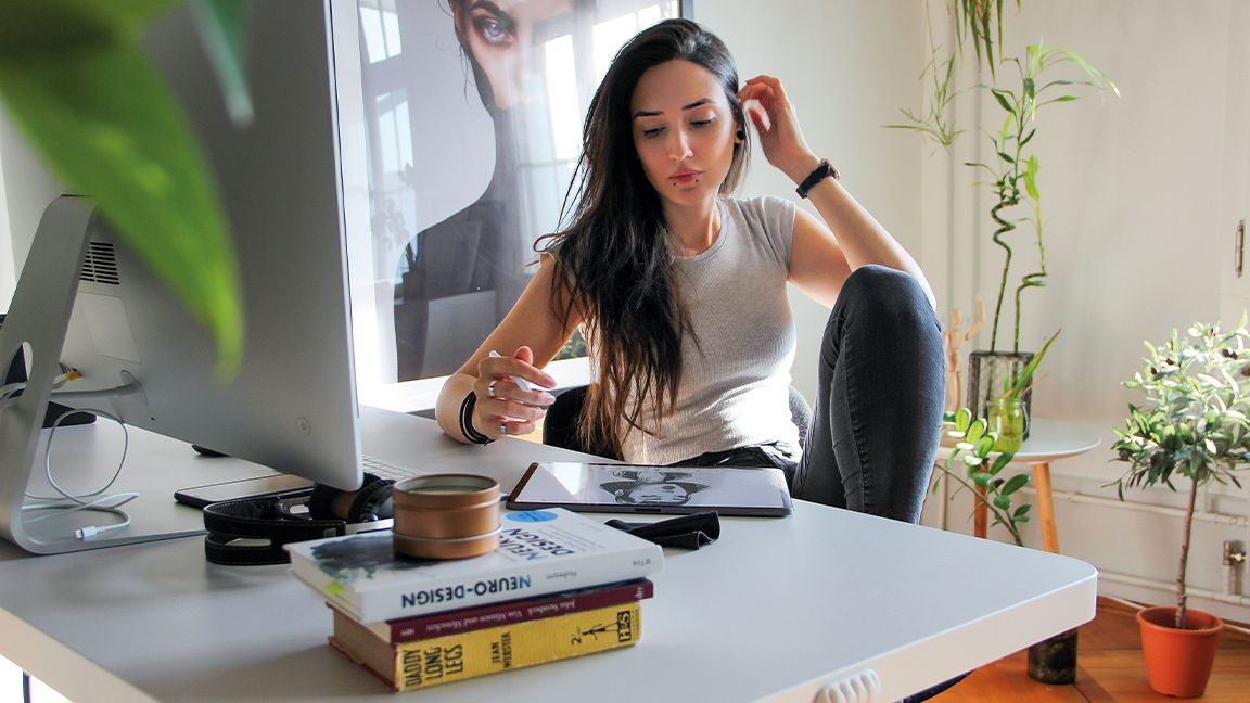 Artist in residence, a woman sits at an art desk with a cat