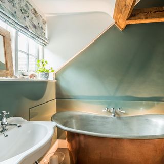 Green bathroom in The Stable, Wiltshire, with green walls and a green rolltop bath