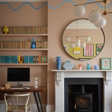 A living room with a working from home desk and a fireplace painted in Benjamin Moore's Terra Bella AF-195 with a wavy feature in Blue Wave 2065-50