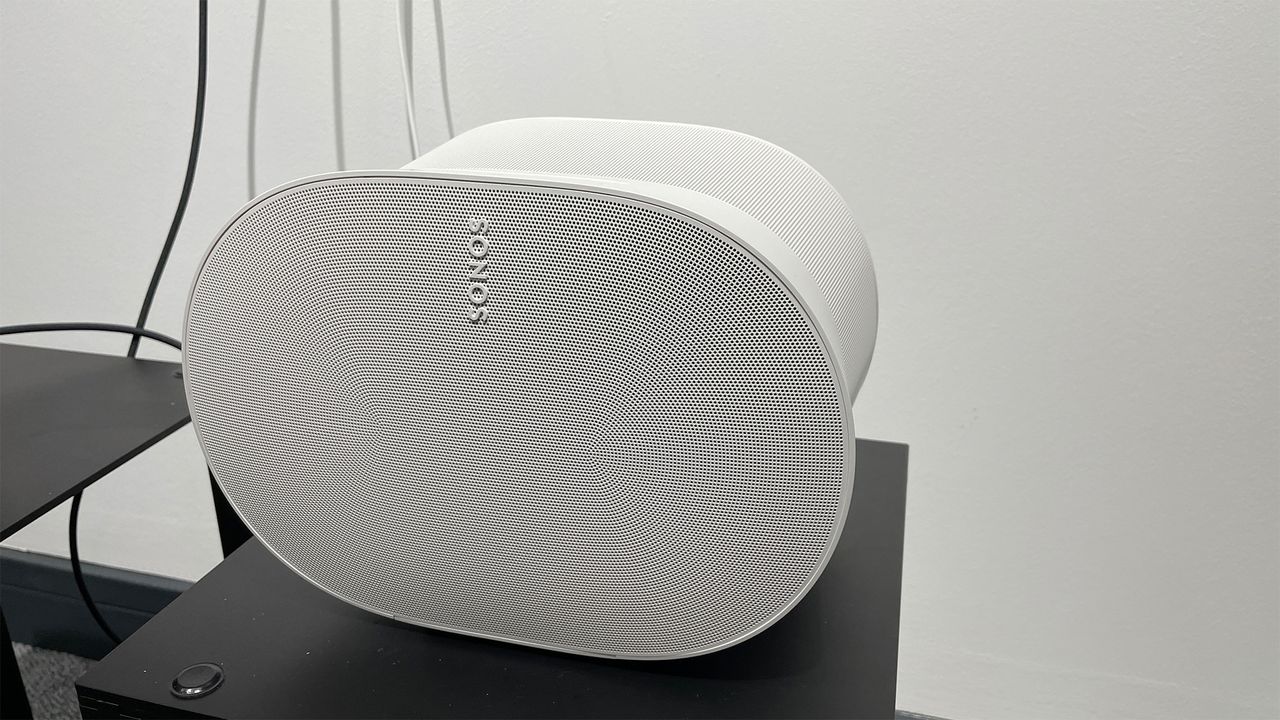 The front of a white Sonos Era 300 smart speaker. There are some wires visible in the background.