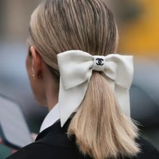 a woman with coloured blonde hair pinned up with a white chanel bow