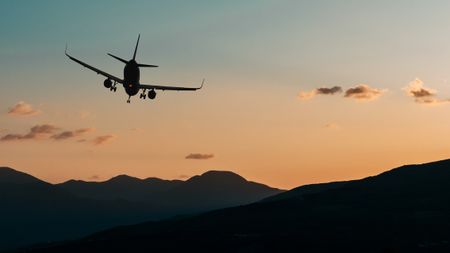 A plane flying over a mountain at sunset