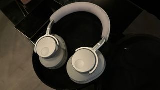 A white pair of Camridge Audio Melomania P100 headphones on a black background.